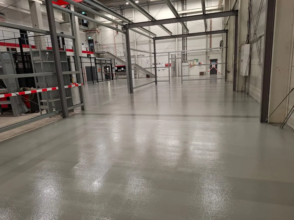 Frisch beschichteter, glänzender Industrieboden in einer Logistik- und Produktionshalle mit Stahlbau